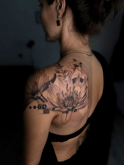flower back tattoo in black with geometric elementsdone by